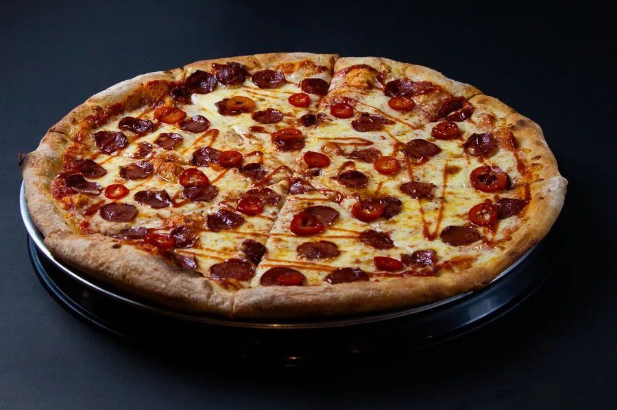 Pizza de pepperoni entera sobre fondo negro, fotografía gastronómica propia